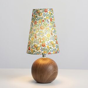 Illuminated modern floral table lamp glowing on tabletop, showcasing warm botanical lighting from fabric shade