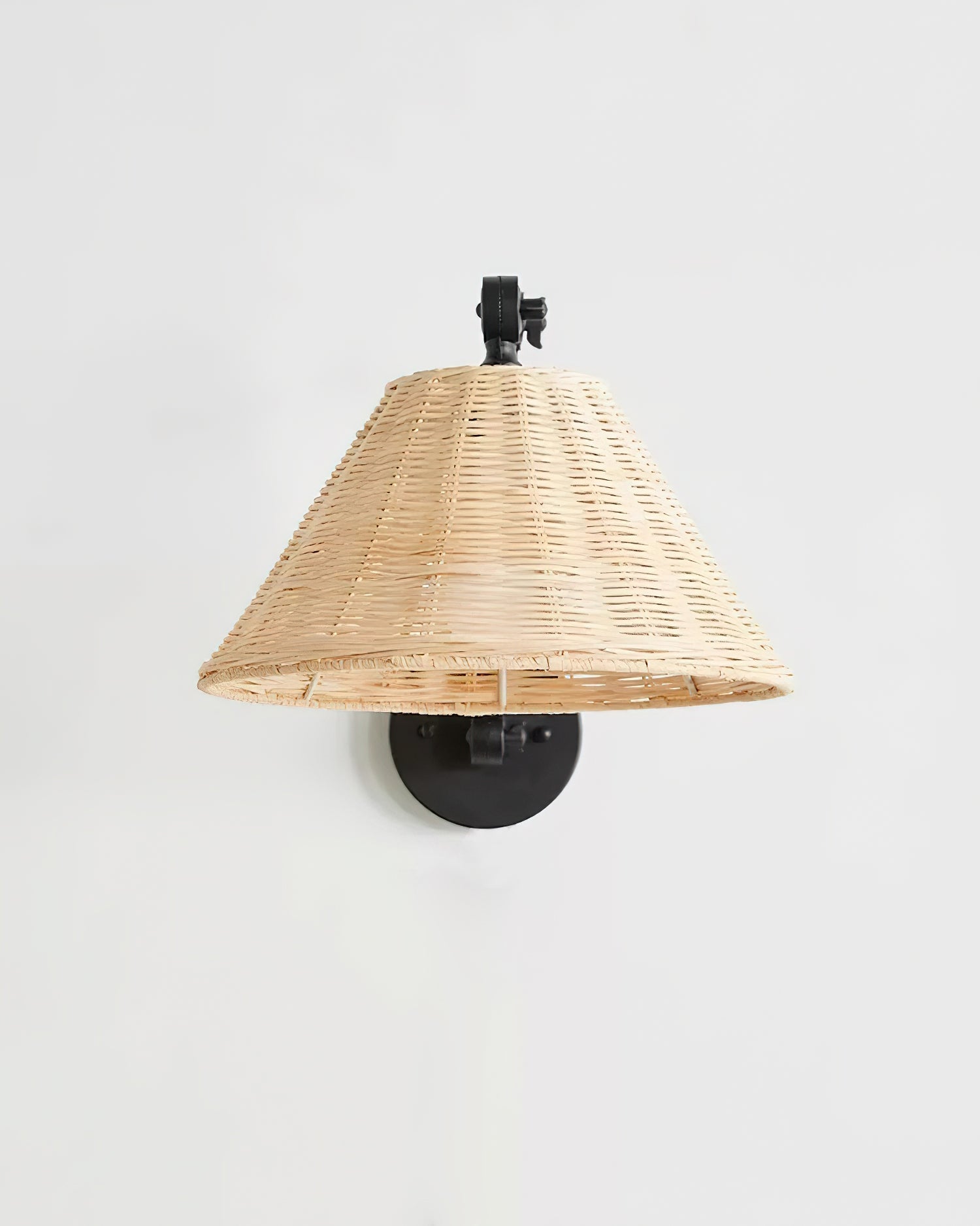Matte black metal swing arm wall sconce with natural rattan shade mounted on interior wall
