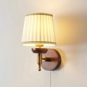 Blixen wall sconce close-up detail showing brass hardware and decorative gold trim on pleated shade