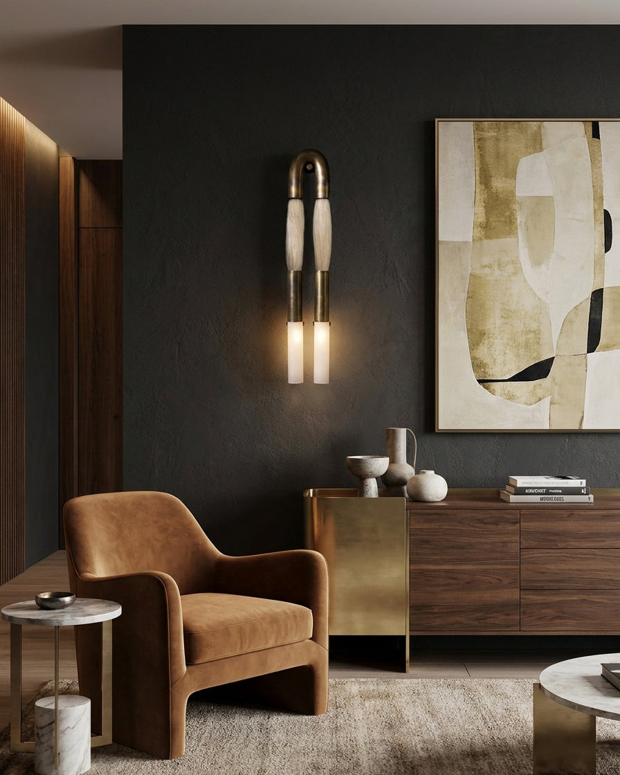 Branwick sculptural wall sconce beside leather armchair and wooden sideboard in dark luxury living room setting
