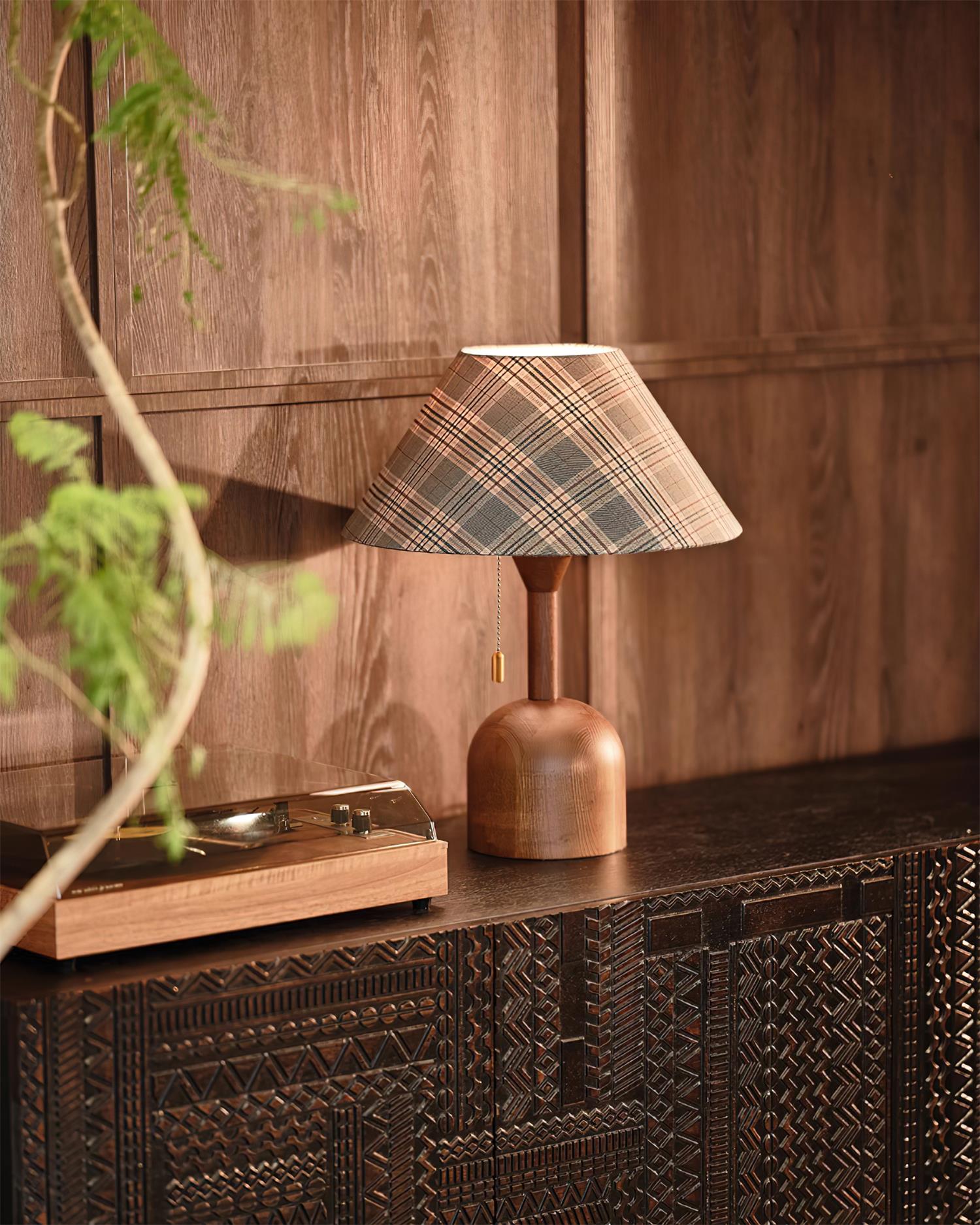 Wooden cabin table lamp beside carved wood cabinet with green plant styling