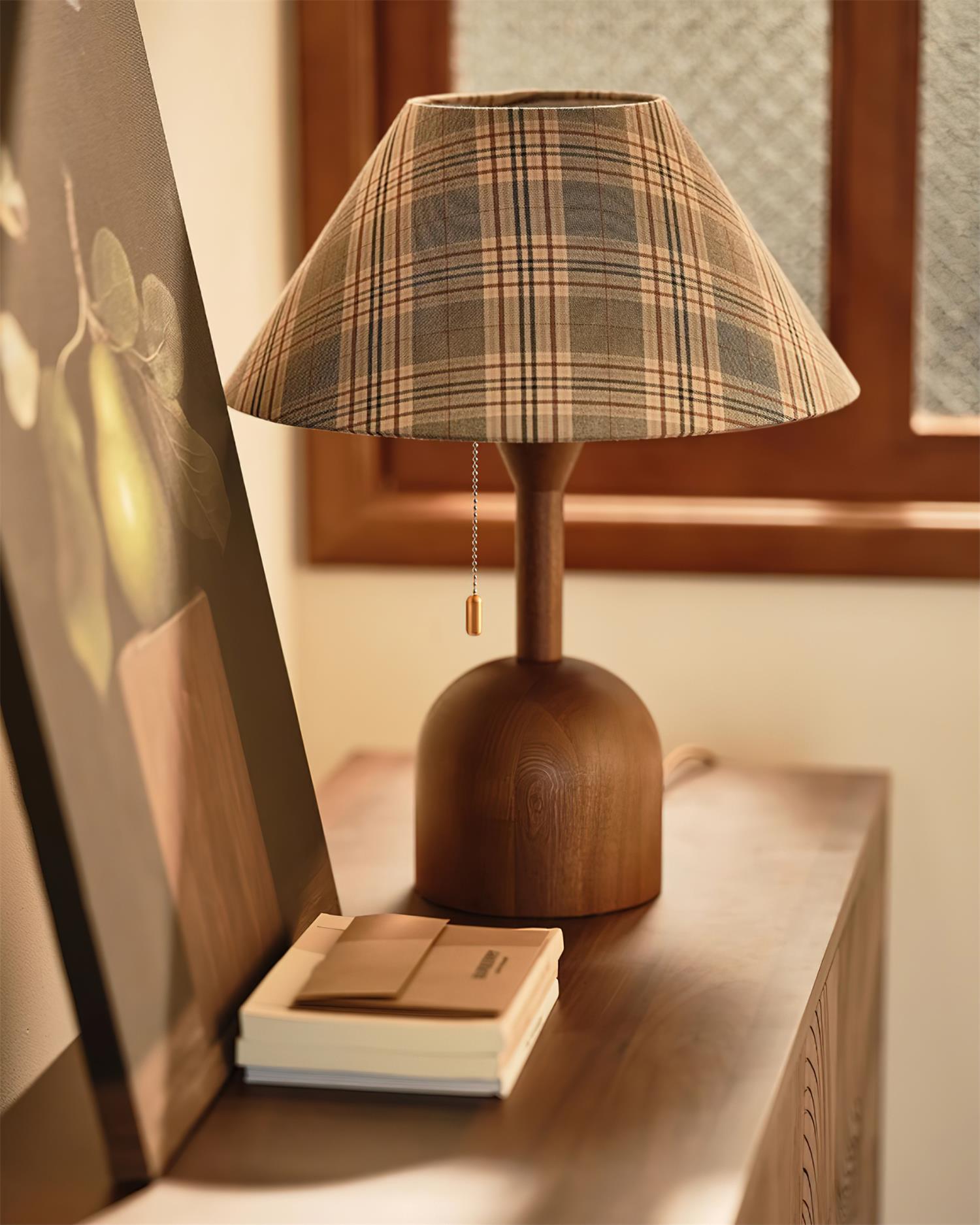 Cabin plaid table lamp on wooden console with stacked books and framed art
