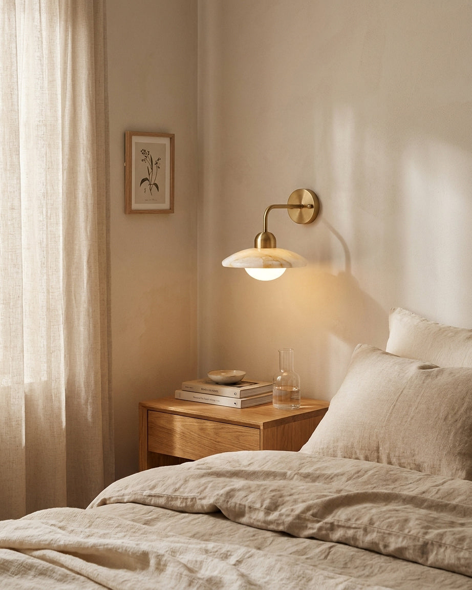 Carolia alabaster wall sconce as bedside reading light paired with wood nightstand and linen bedding