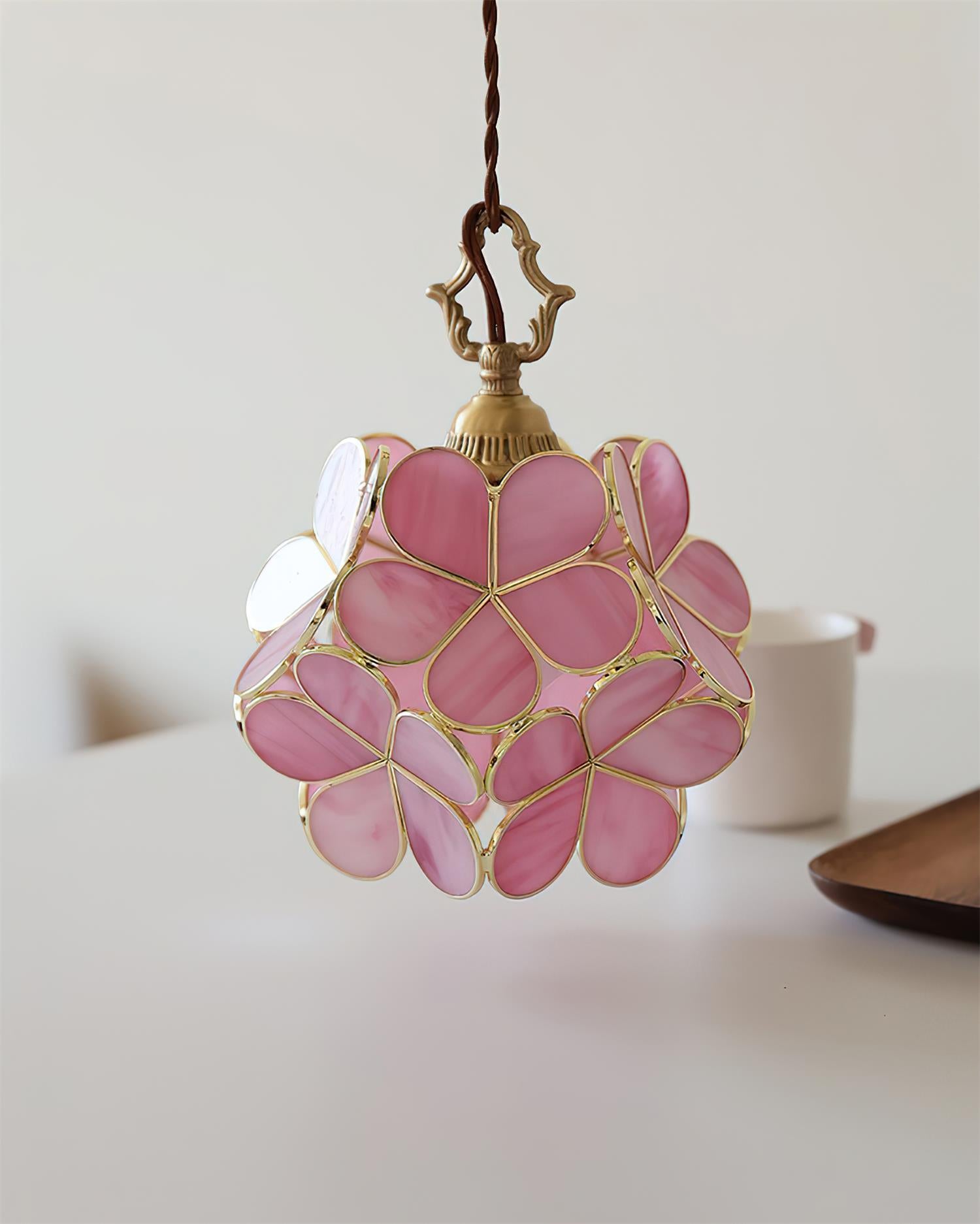 Three-quarter close-up view of pink stained glass floral pendant lamp with gold trim
