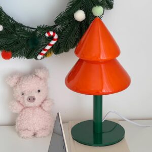 Contemporary Christmas tree table lamp styled with festive wreath and holiday decorations on home desktop