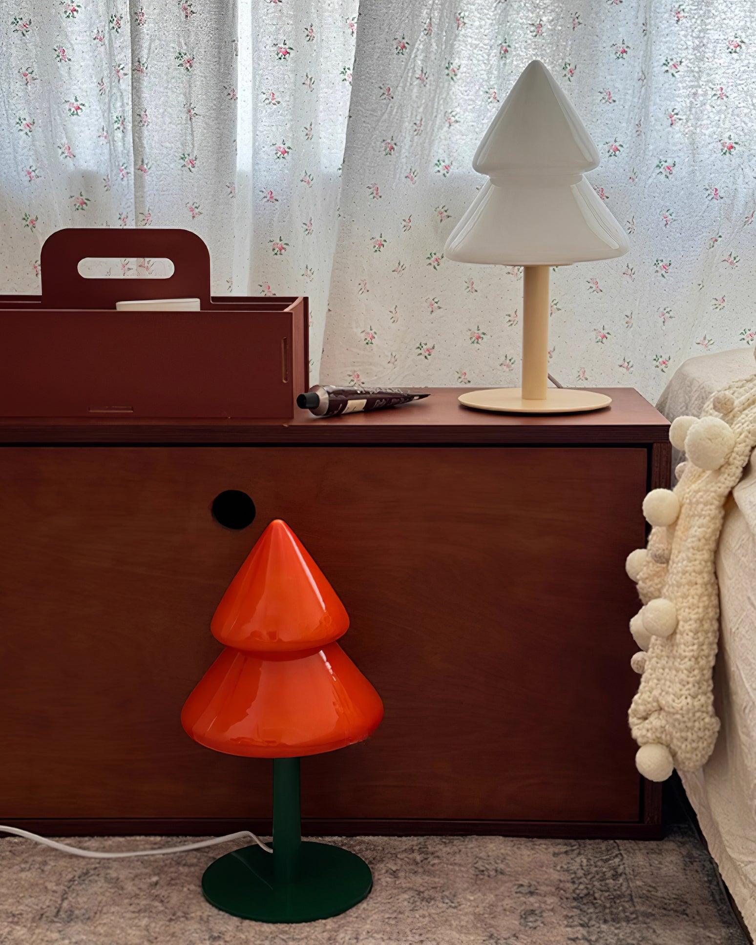 Two modern Christmas tree lamps in white and orange shades placed together in minimalist bedroom corner