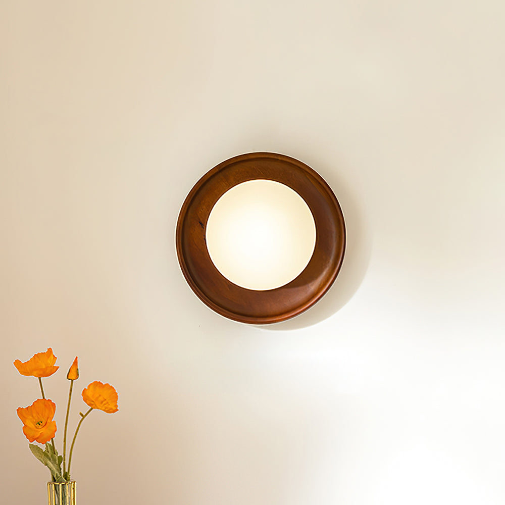 Walnut finish round wall sconce mounted beside home decor with warm ambient lighting