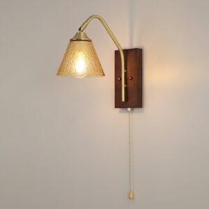 Vintage wall sconce with warm amber textured glass shade and mid-century modern brass hardware mounted on wall