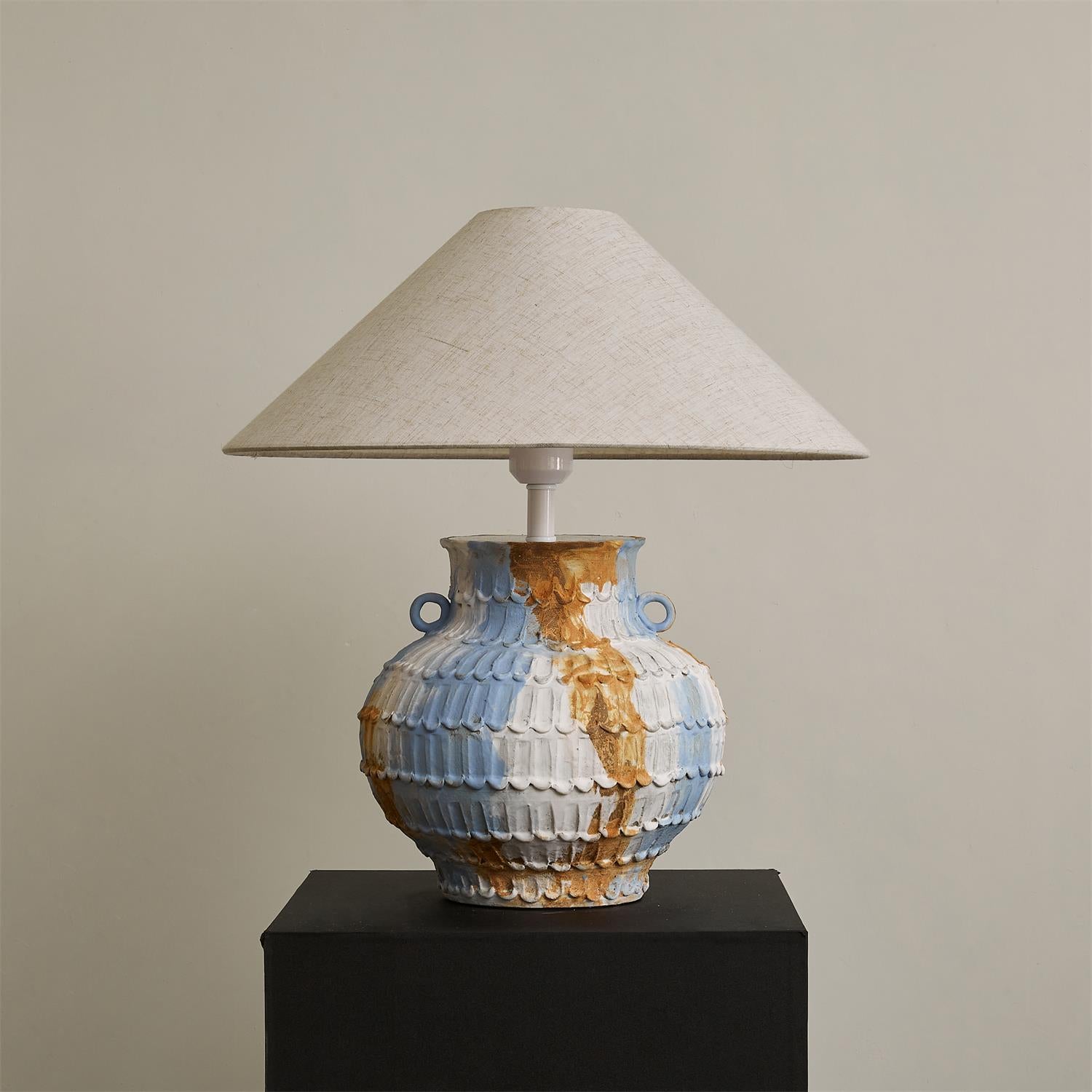Grazie ceramic table lamp with textured hand-thrown pottery base in blue-beige tones paired with natural linen cone shade on display - modern artisanal table lighting