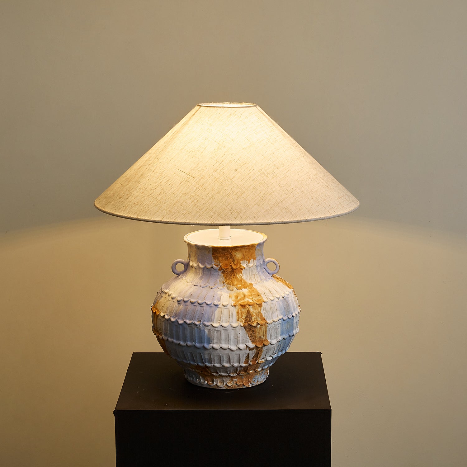 Illuminated Grazie ceramic table lamp low angle view with warm glowing linen cone shade and compact sculptural hand-thrown pottery base - modern artisan table lighting