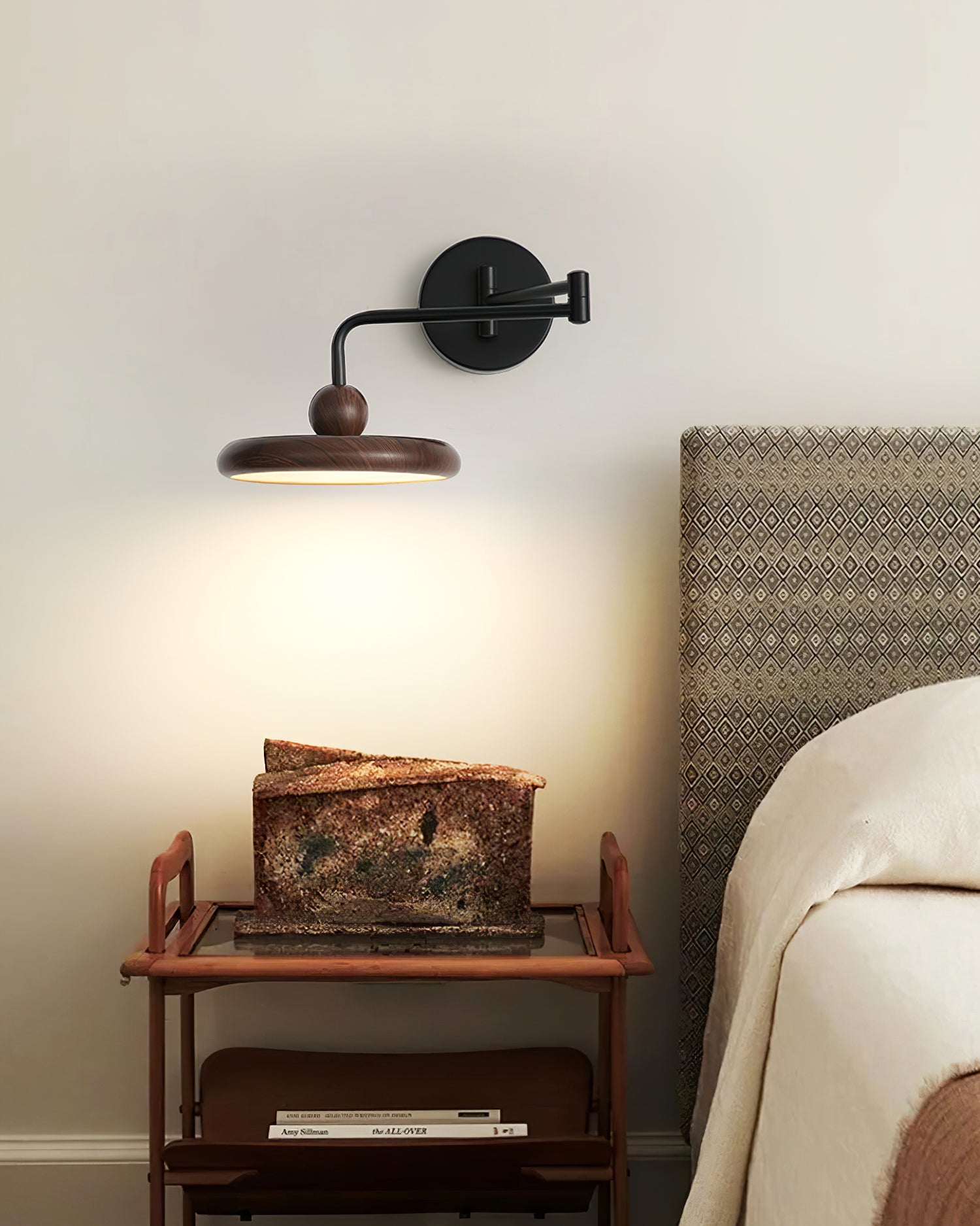 Contemporary wall sconce positioned at bedside table emitting warm glow light for reading and relaxation