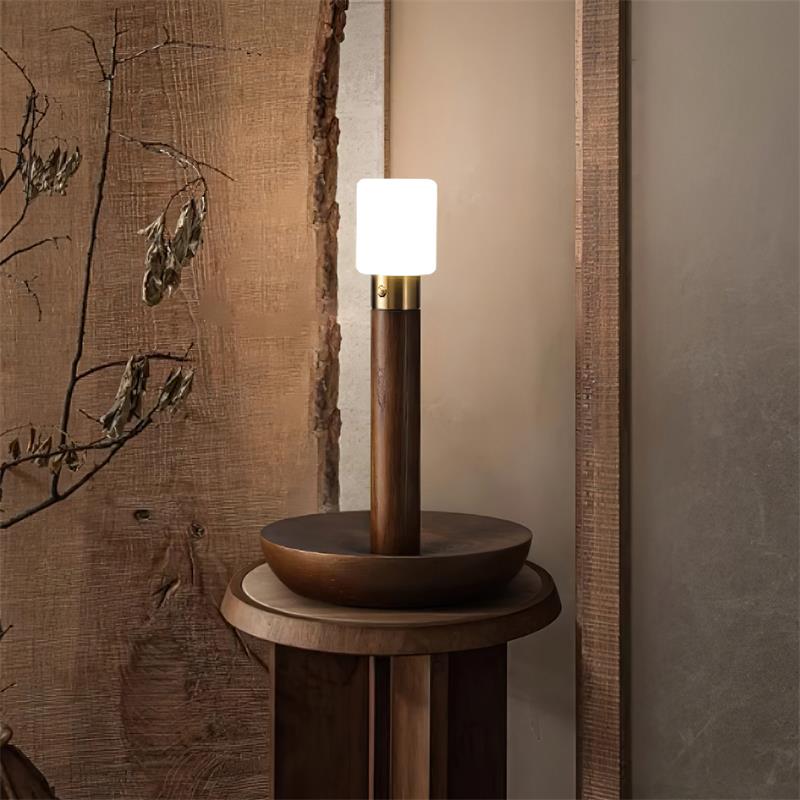 Dark walnut wood table lamp with frosted shade on rustic wooden side table with vintage wall accents