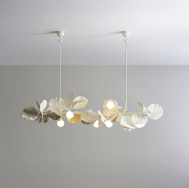 Close-up detail of Liria linear chandelier showing hand-carved ivory-white gypsum-resin leaf shades with warm E14 bulbs