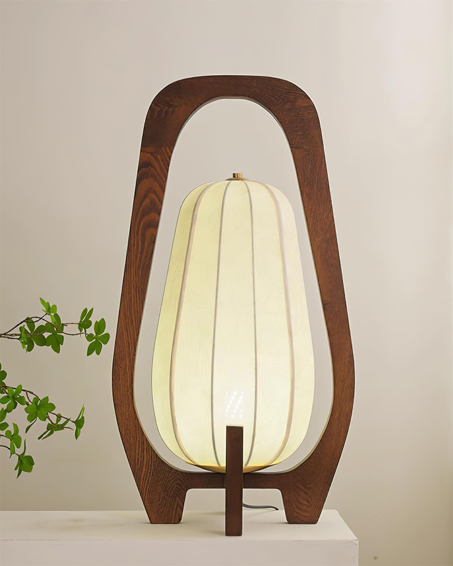 Arched wooden frame table lamp with unlit cream fabric shade showing vertical stitching panels, low-angle front view
