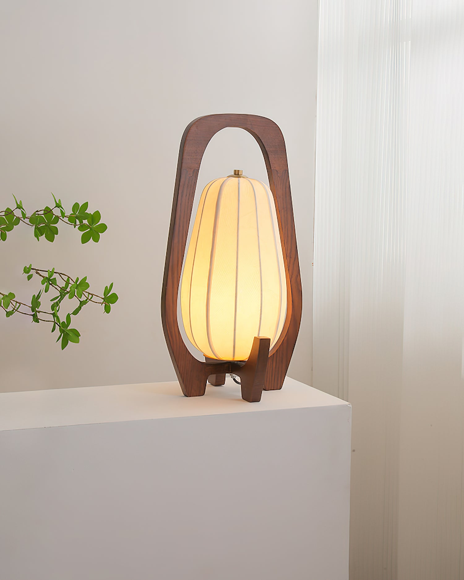 Wooden table lamp with dark wood finish three-quarter side view beside sheer window curtains, contemporary Nordic design