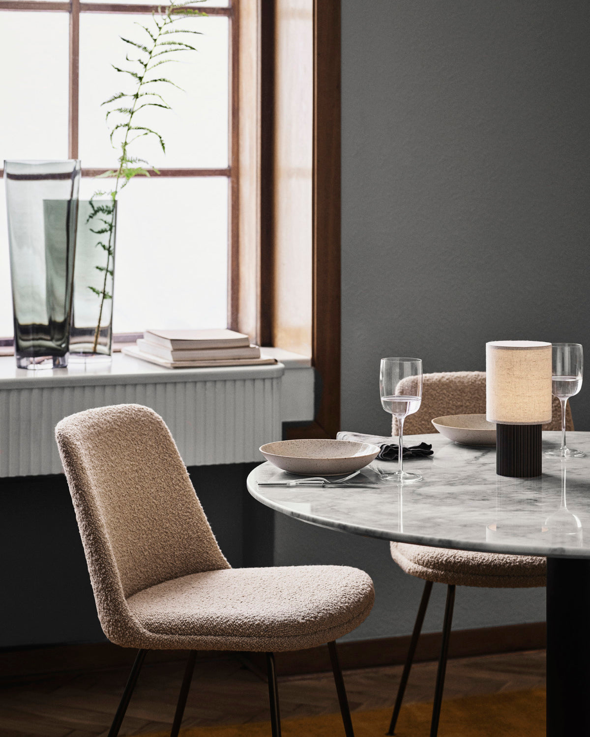 Lit table lamp on round marble dining table in window-side dining nook, warm minimalist home décor with soft 3000K lighting