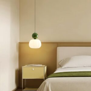 Modern pendant light in green finish installed above bedside table in contemporary bedroom - eye-level interior view