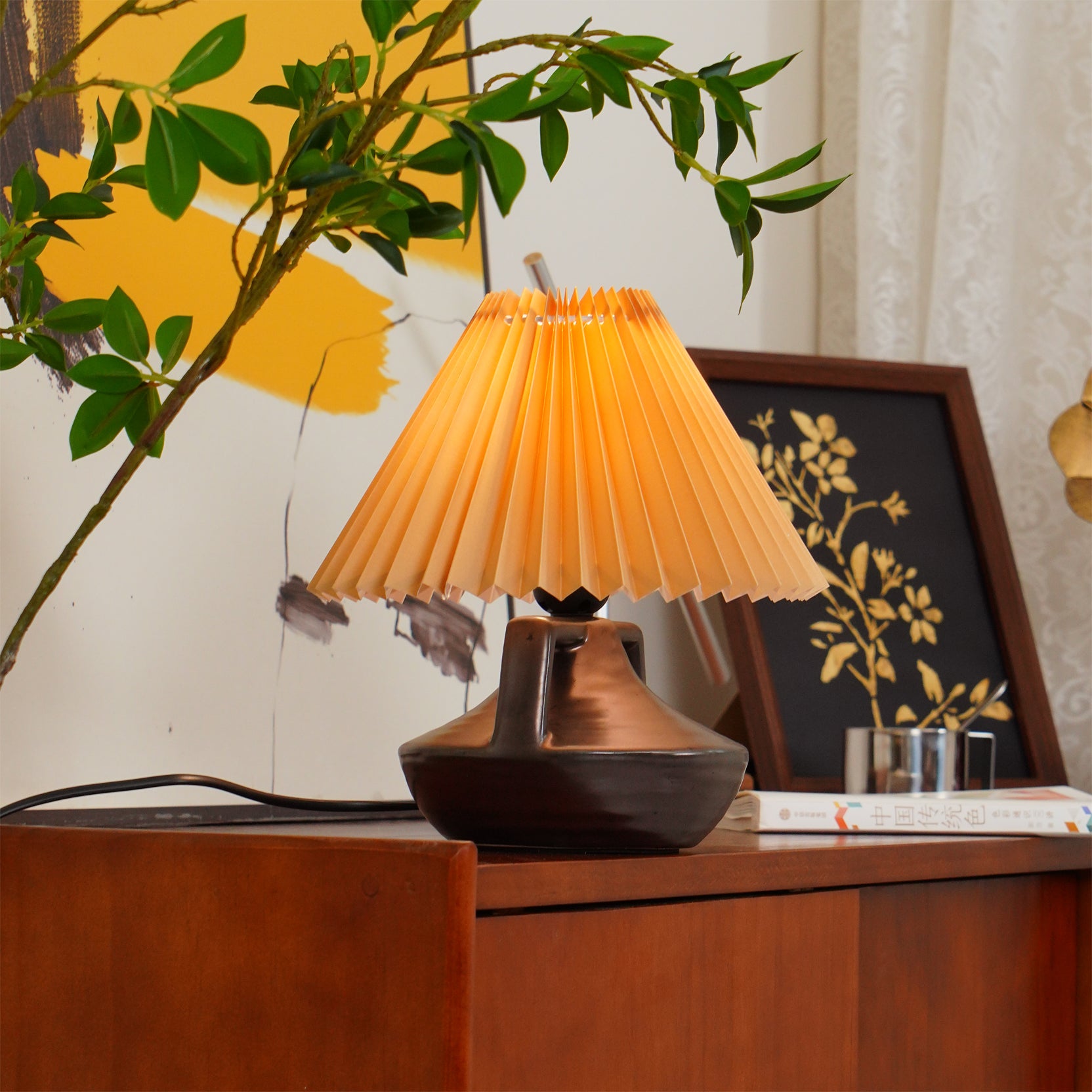 Navia Pleated Table Lamp in home interior setting on side cabinet with warm lighting and decor