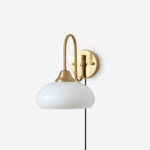 Textured glass plug-in wall sconce with gold brass base and white milk glass dome shade, front three-quarter studio view