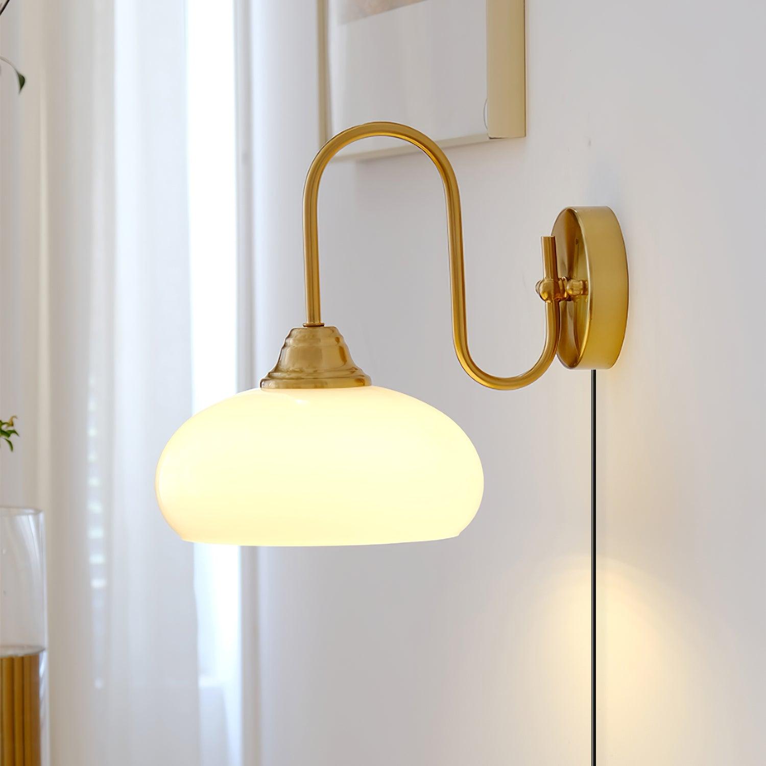 Illuminated gold brass plug-in wall sconce with warm glowing textured glass diffuser in bright indoor living space