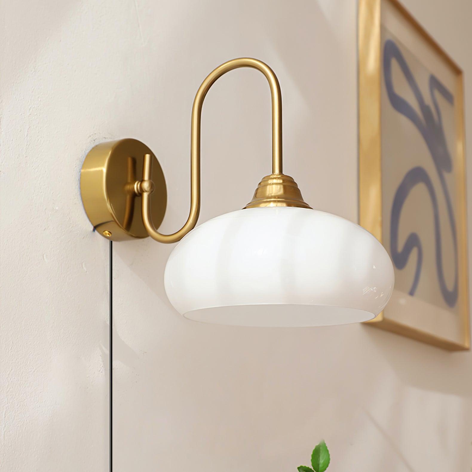 Ribbed glass plug-in wall light with brass gold metal base mounted on wall with framed artwork, front three-quarter view
