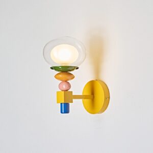 Popella wall sconce side profile showing yellow backplate, stacked color-blocked beads, and illuminated clear glass globe