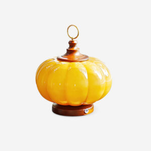 Pumpkin glass table lamp front view with amber ribbed glass body, walnut wooden finial and polished brass ring, studio white background