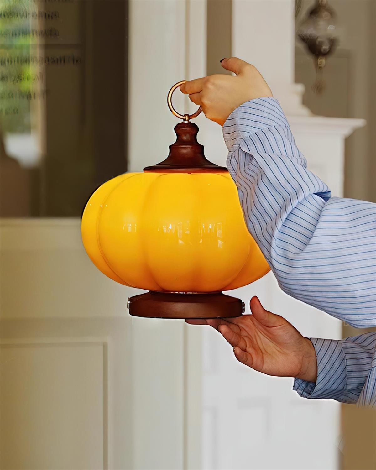 Portable pumpkin table lamp held in hands low three-quarter angle view in home corridor showcasing compact portable design