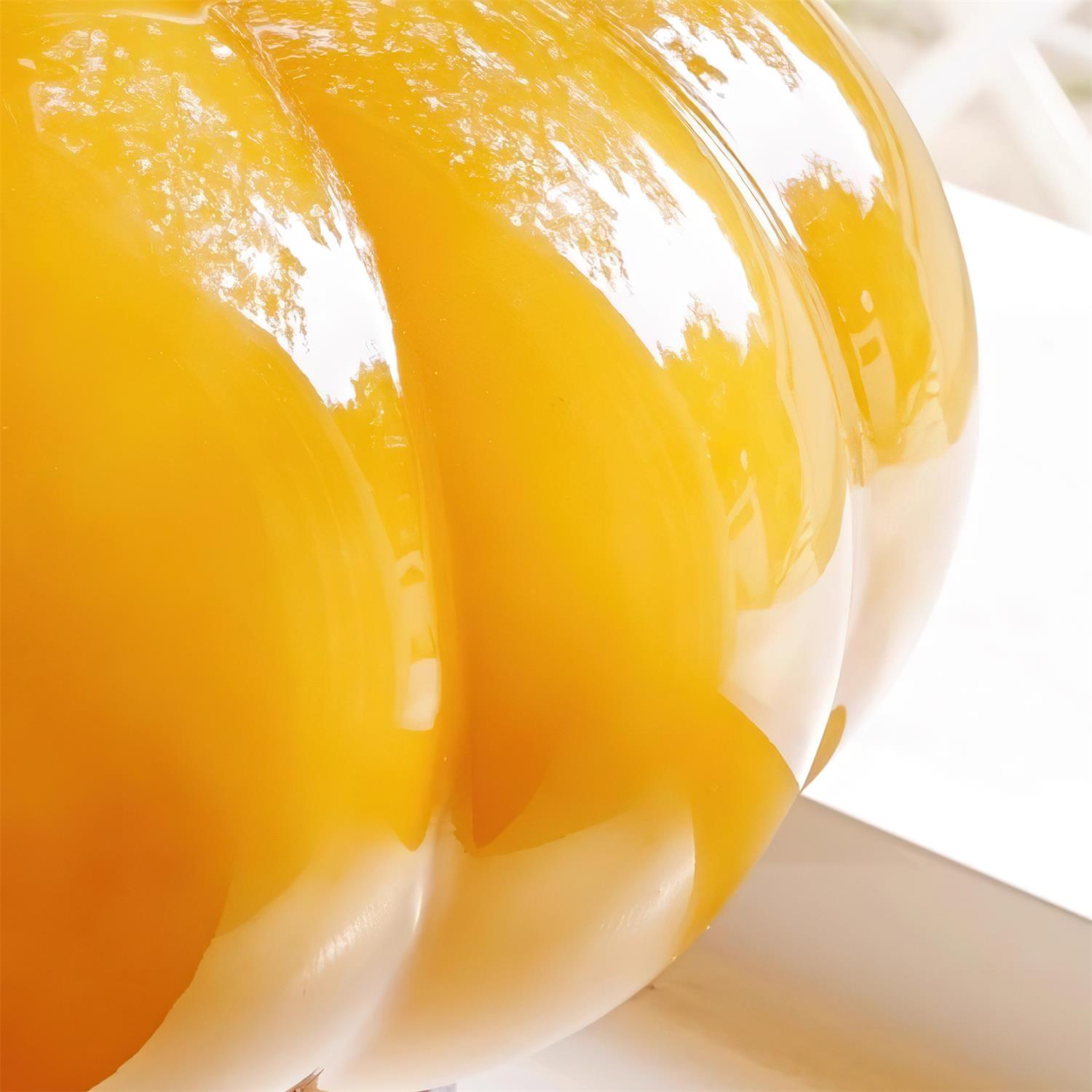 Macro close-up of glossy amber ribbed pumpkin glass surface detail showing light diffusion and premium glass finish