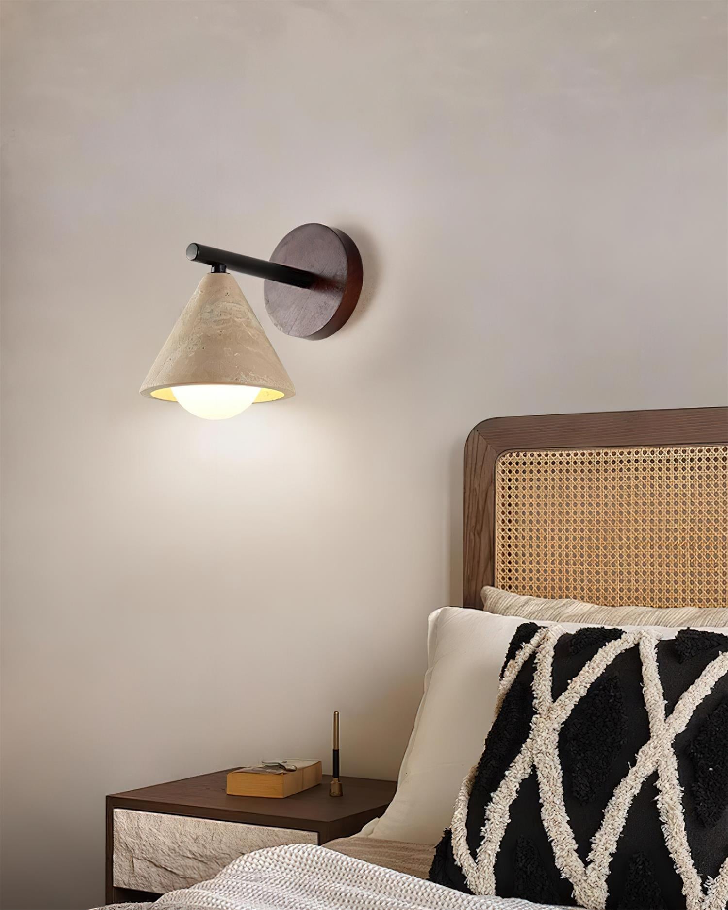 Travertine wall sconce installed in Nordic bedroom above rattan bedside table