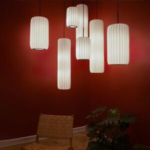 Multiple Rossau pendant lights in modern dining room interior, warm ambient lighting over red accent wall