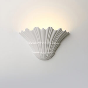 Modern shell wall sconce installed on gray interior wall emitting warm uplight