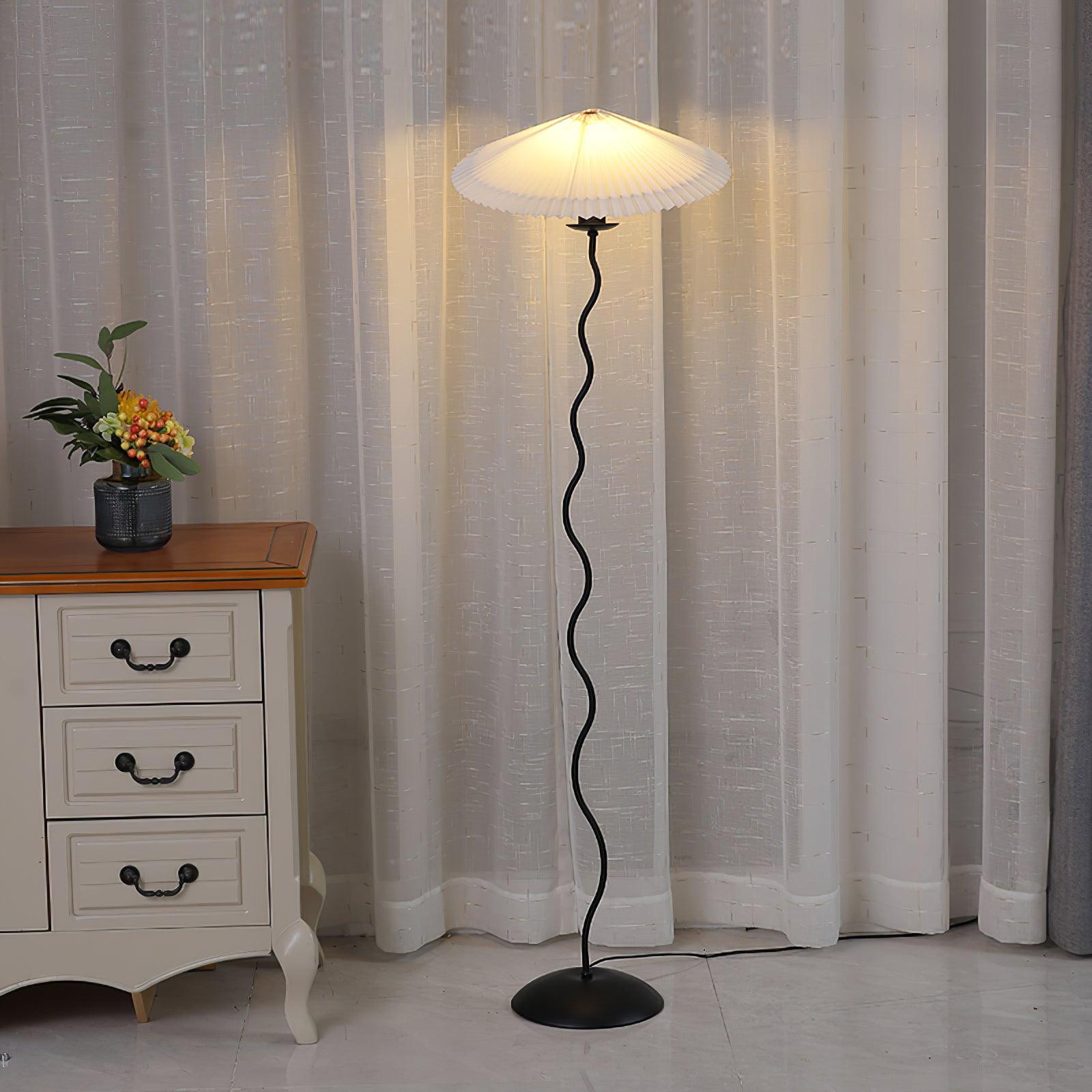 Wavy pole modern floor lamp with pleated fabric shade - warm ambient lighting in contemporary interior with drawer cabinet and curtains