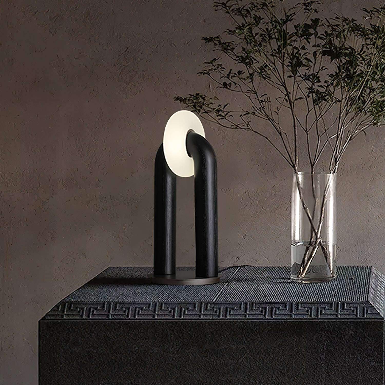 Black matte Teelo lamp with white frosted shade on stone tabletop next to glass plant vase, minimalist oriental style