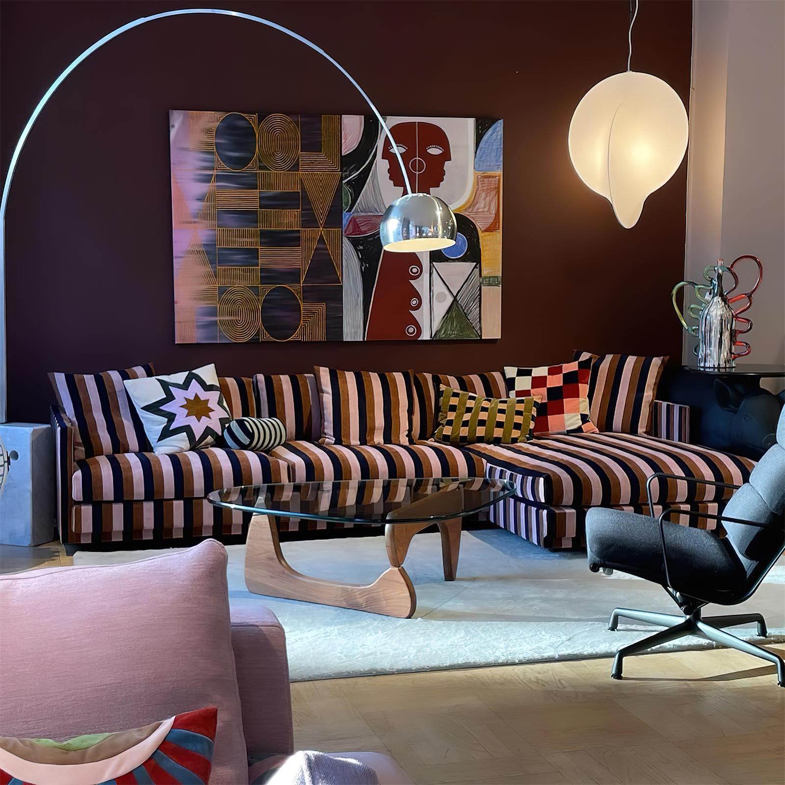 Arc floor lamp with silver shade and curved metal pole beside vibrant patterned sofa