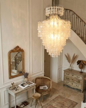 Tirenza shell chandelier installed in French vintage staircase foyer with cream walls and black wrought iron stairs, demonstrating elegant entryway lighting