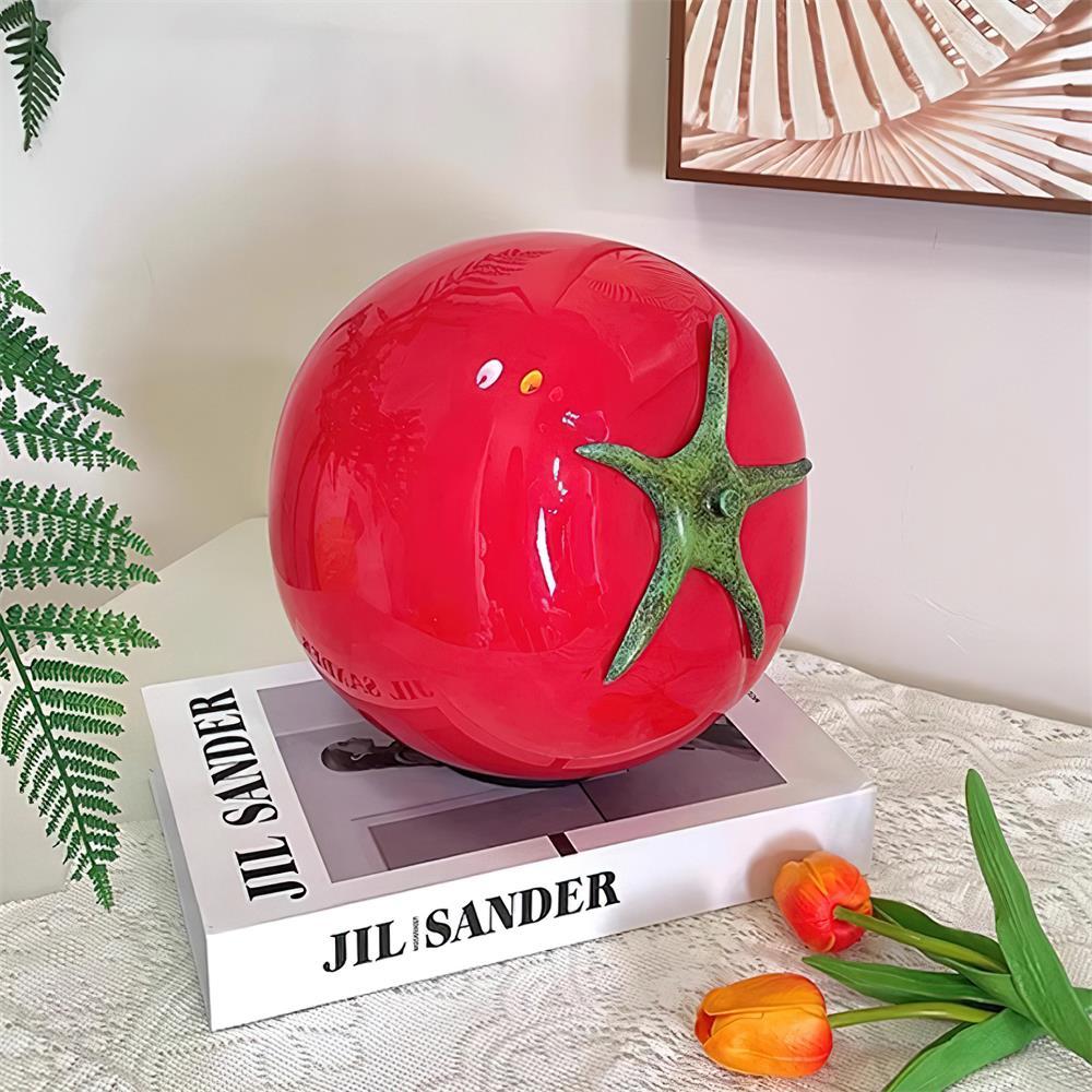 Red tomato table lamp displayed on lace tablecloth with fresh flowers and design books - modern interior styling