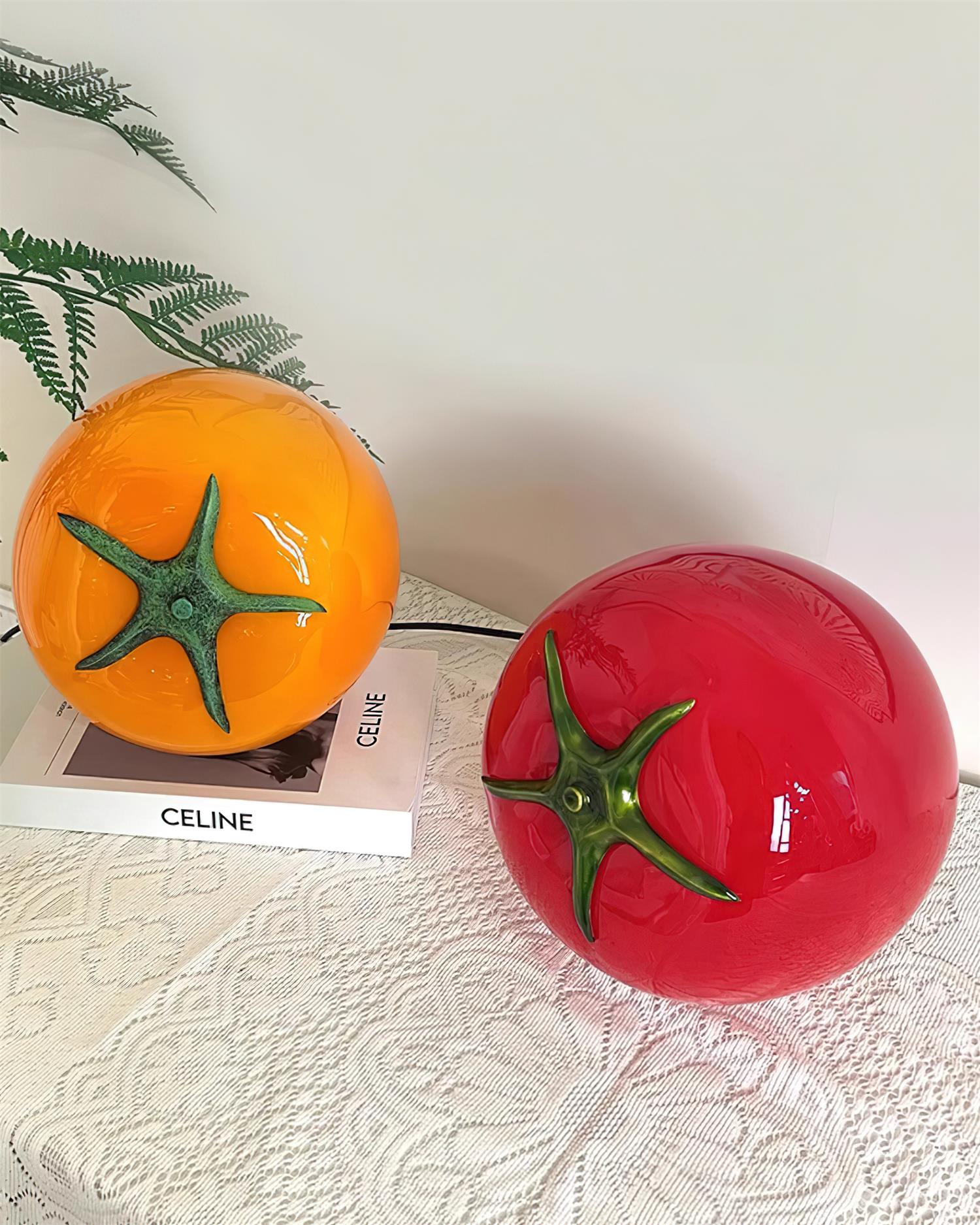 Red and orange tomato table lamps side by side on books - modern glass lamp color comparison