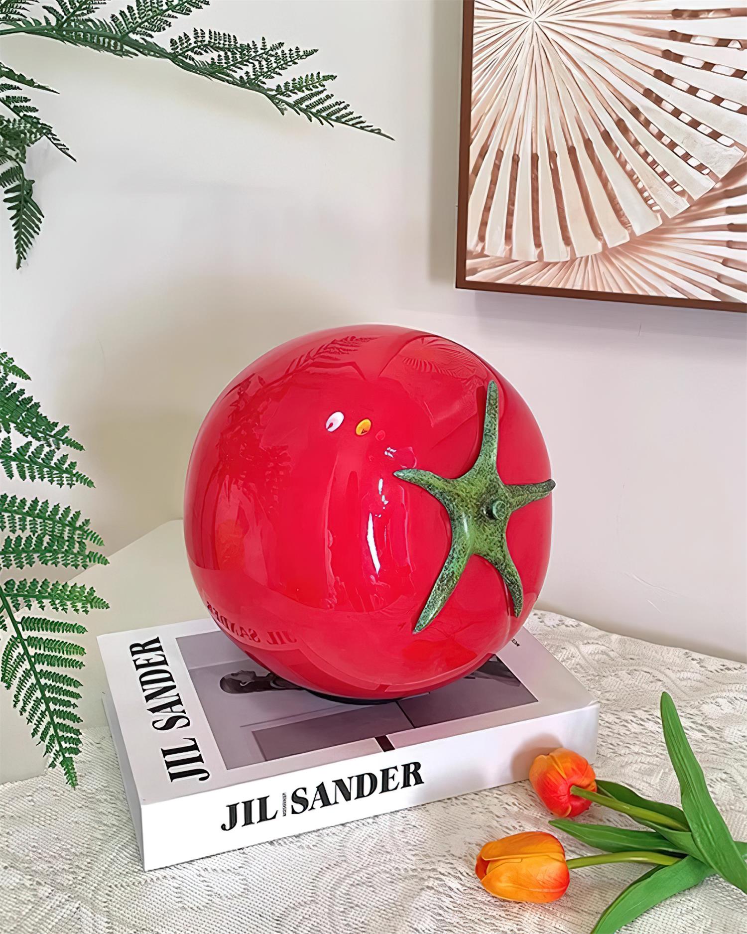 Red tomato table lamp on designer book with ferns and tulips - modern handcrafted lighting accent