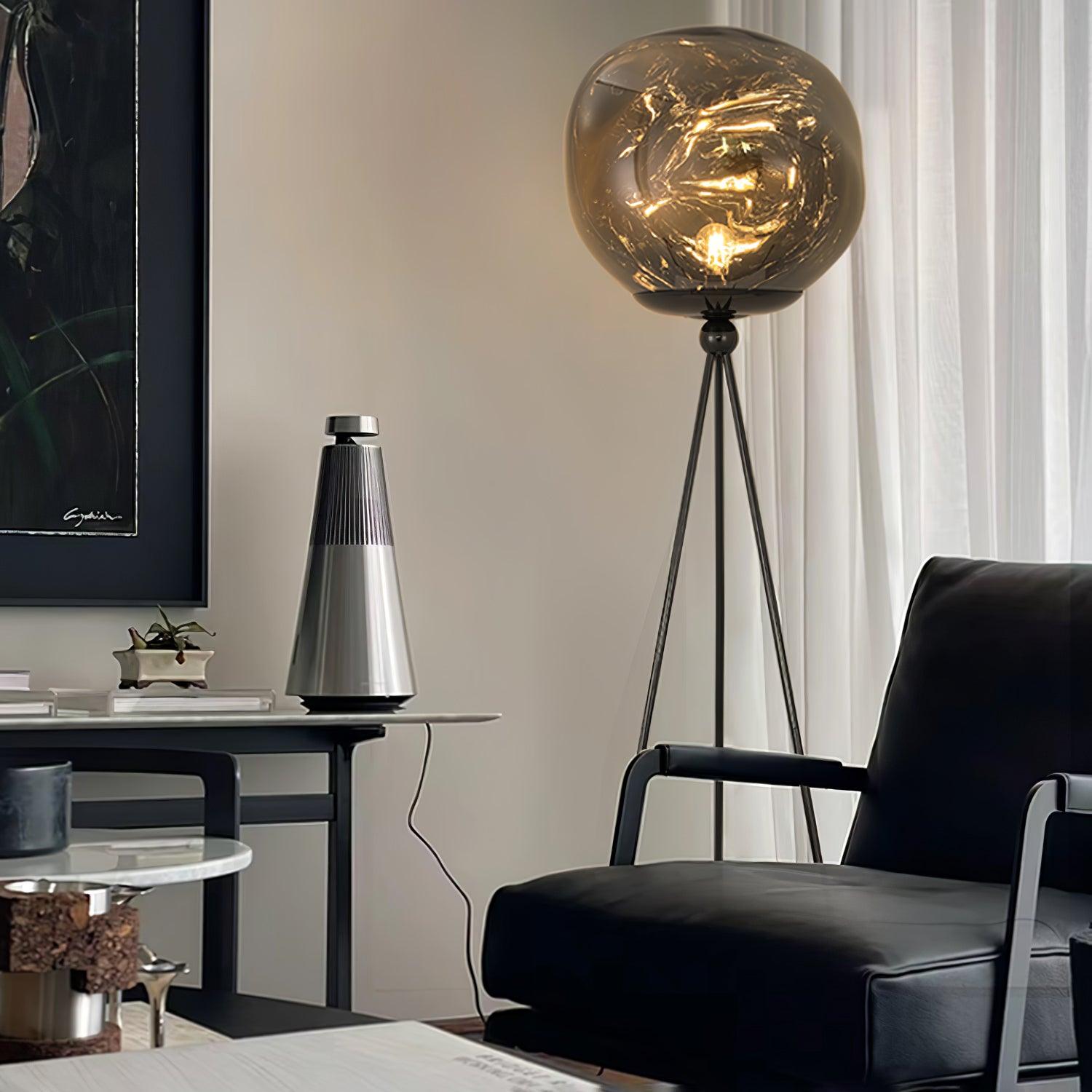Modern gold tripod floor lamp with round molten glass shade in neutral interior design scheme
