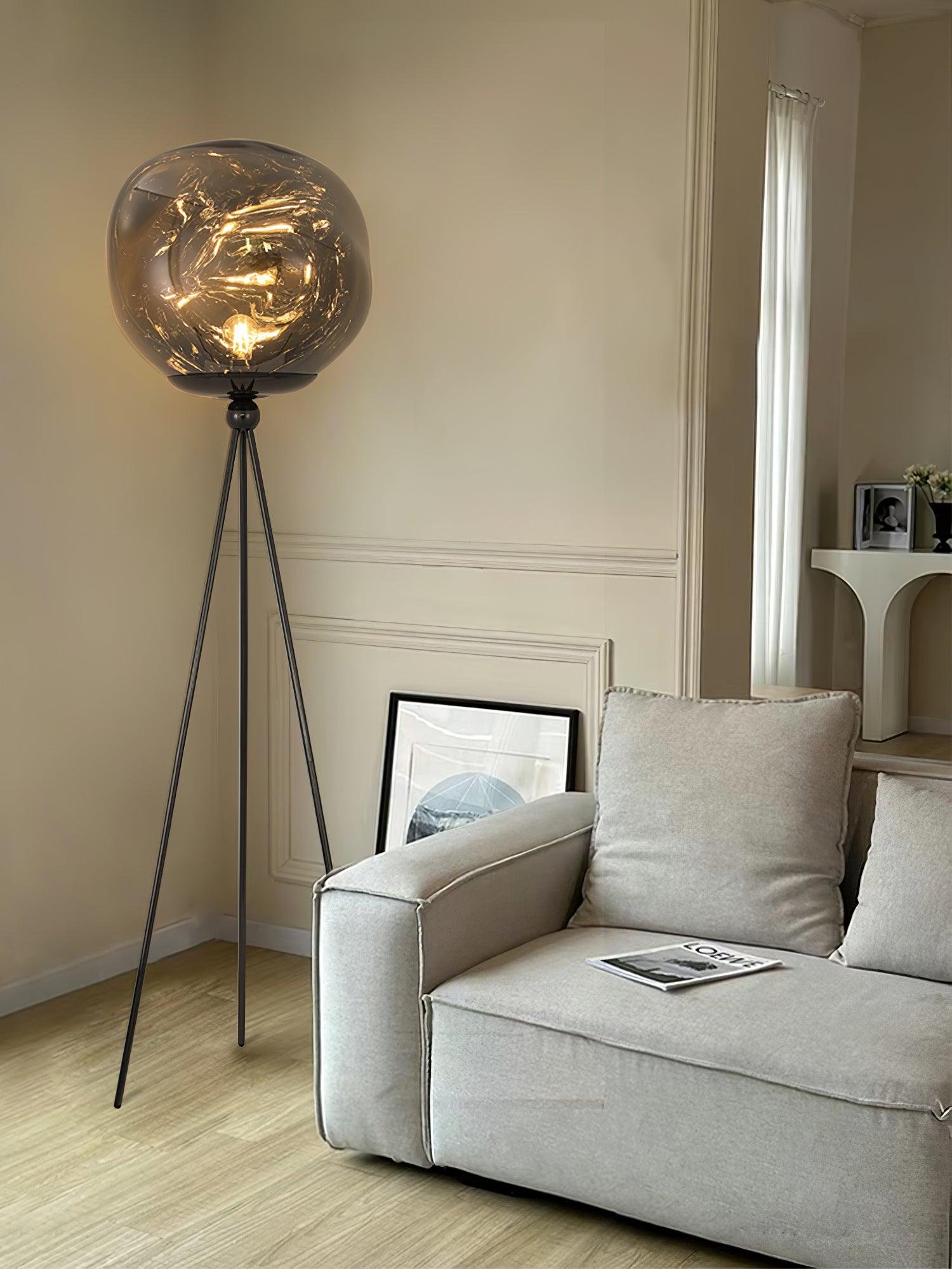 Contemporary tripod floor lamp featuring rose gold stand and artistic molten lava glass lampshade