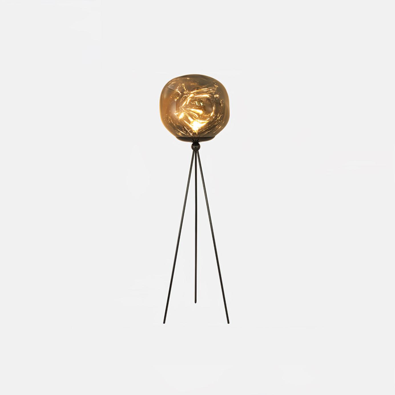 Artistic tripod floor lamp with molten glass shade emphasizing artisanal craftsmanship and design elegance