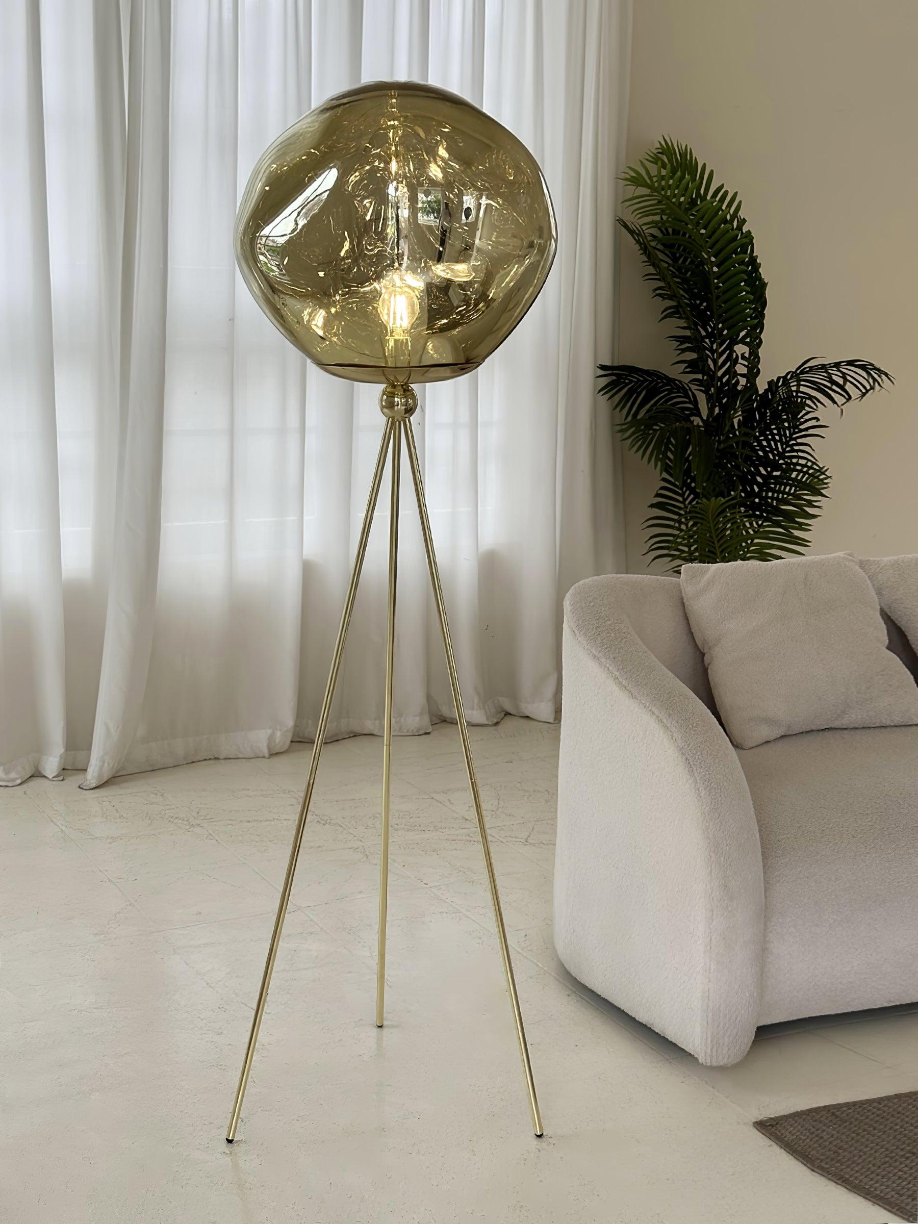 Modern rose gold tripod floor lamp with artistic molten glass shade creating mesmerizing light effect