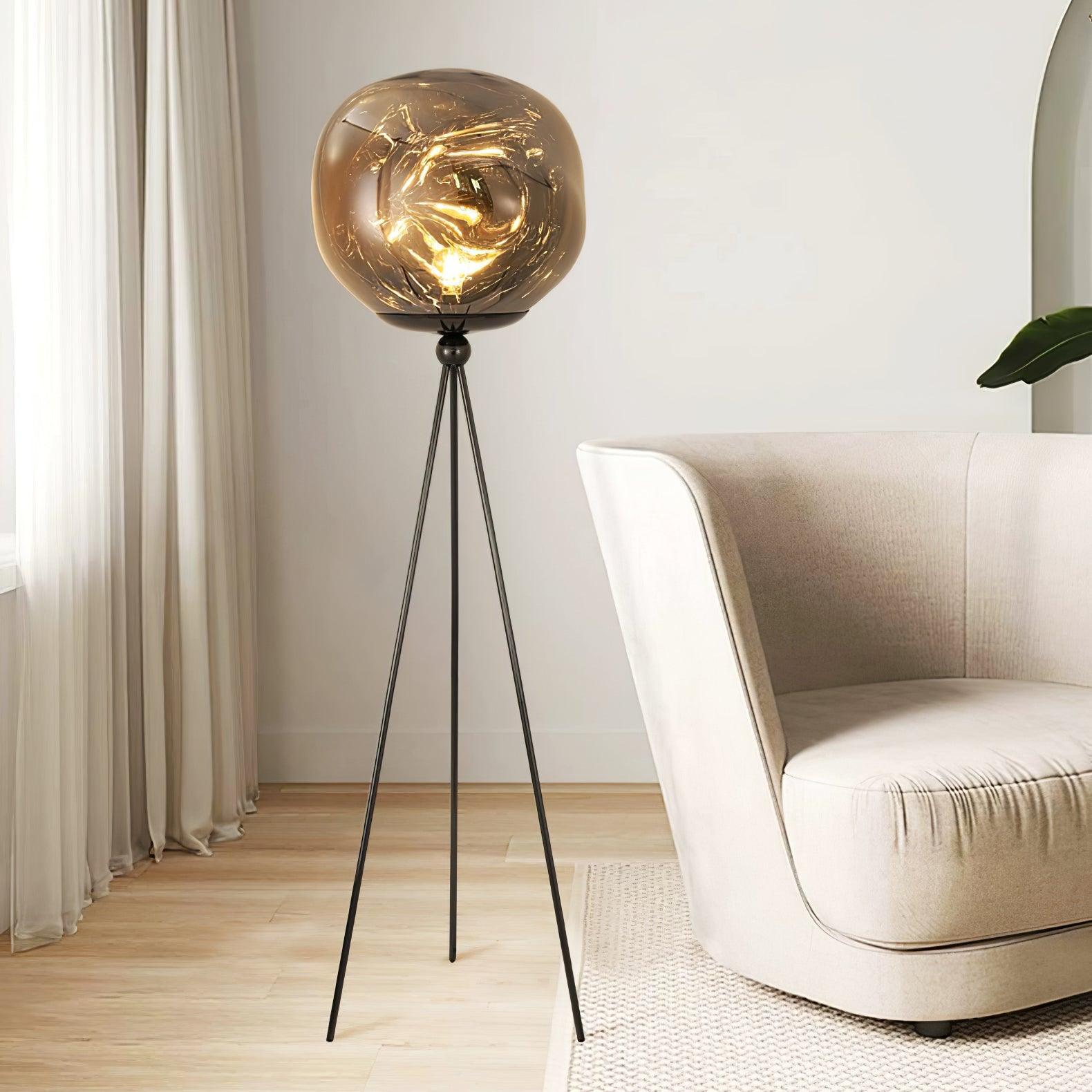 Contemporary tripod floor lamp with black metal stand and decorative molten glass in minimalist interior