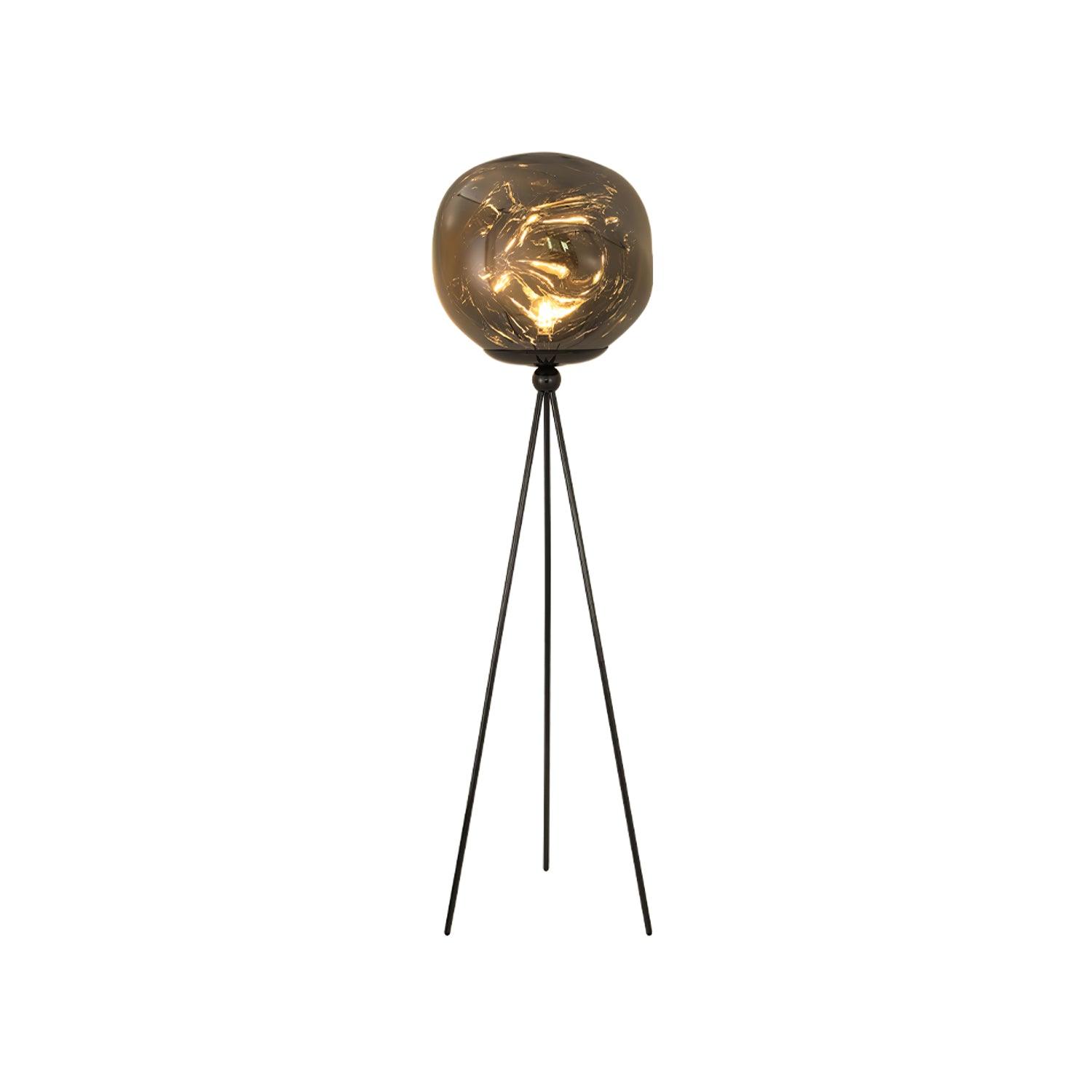 Modern artistic tripod floor lamp featuring unique molten lava glass and three-legged metal frame design