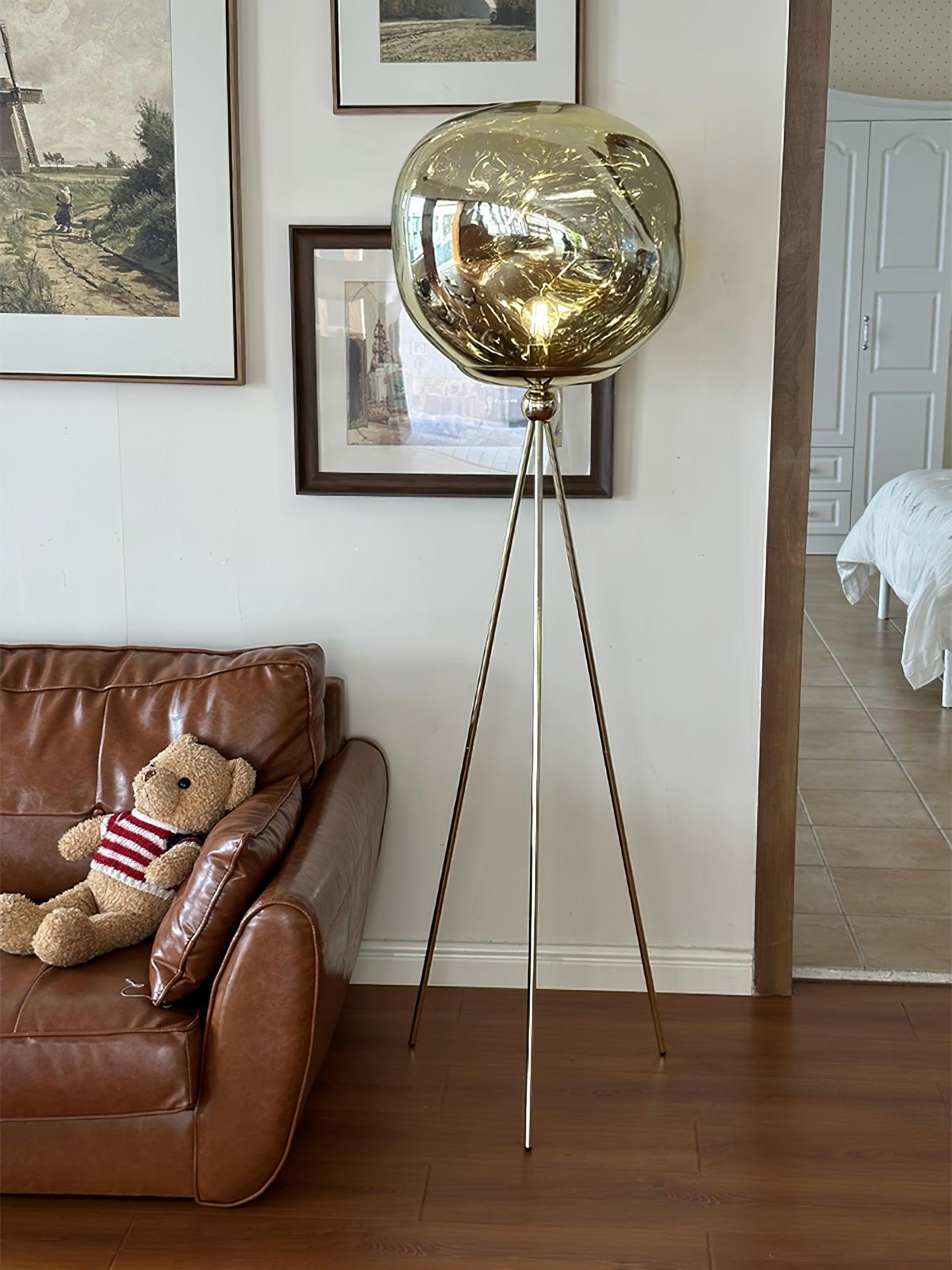 Contemporary black tripod floor lamp with round molten glass shade emphasizing handcrafted quality