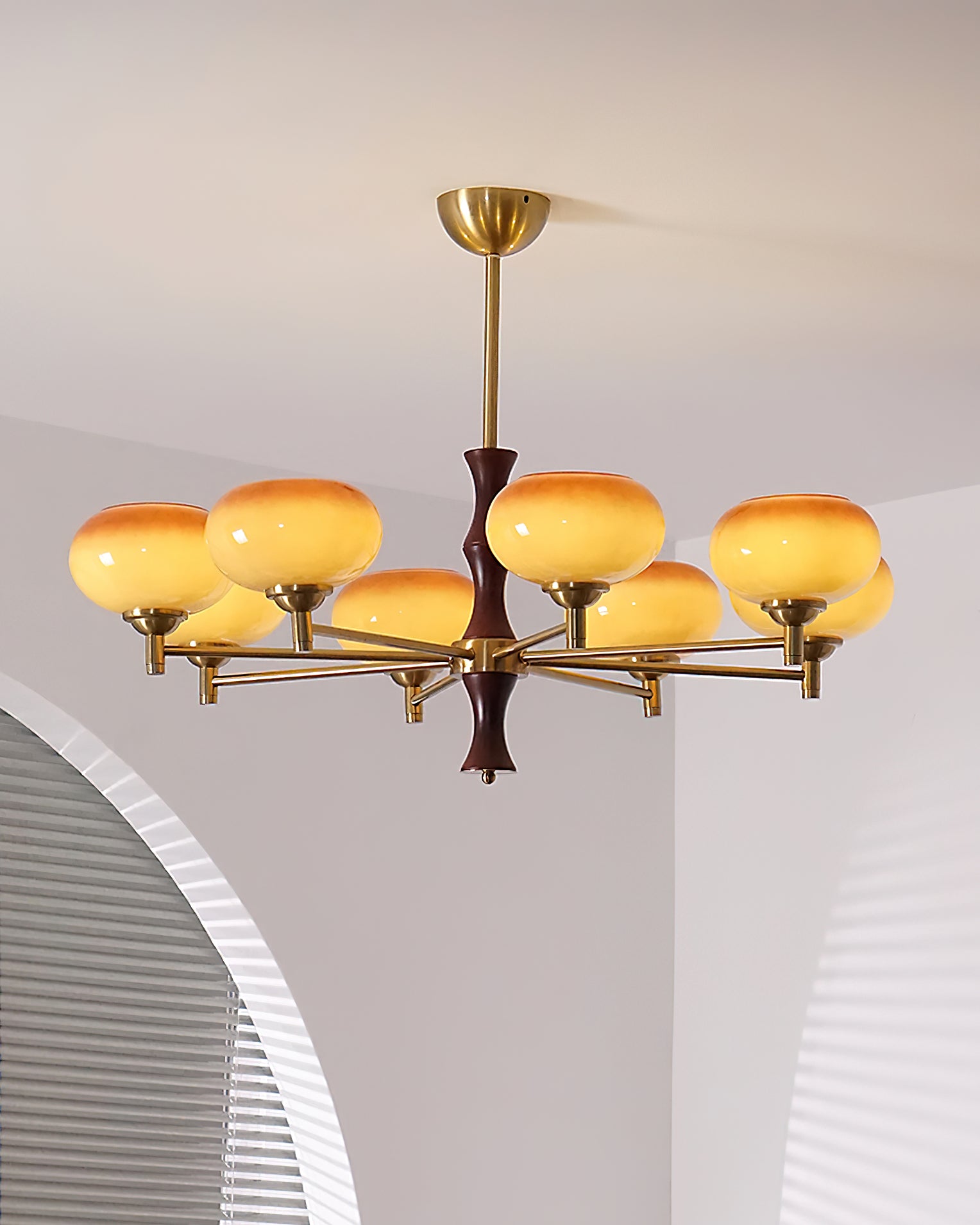 8-head retro chandelier in home space with arched louvered wall, warm amber glass shades, brass frame, and dark wood accent