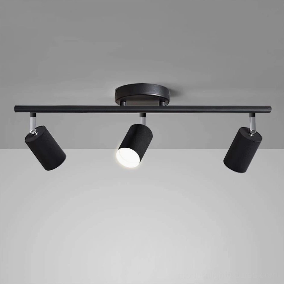 Black track lighting system with 3 adjustable spotlight heads, three-quarter angle view against grey wall