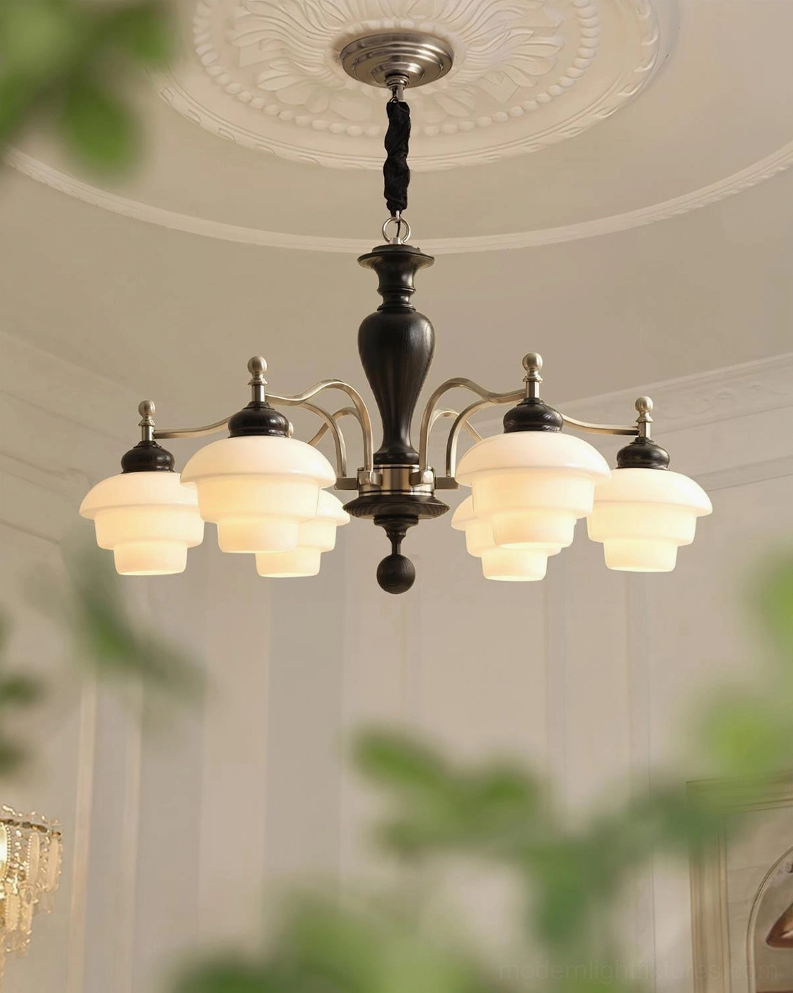 6-light vintage chandelier close-up overhead view in cozy living space with green foliage - black dark wood frame with brushed nickel metal arms