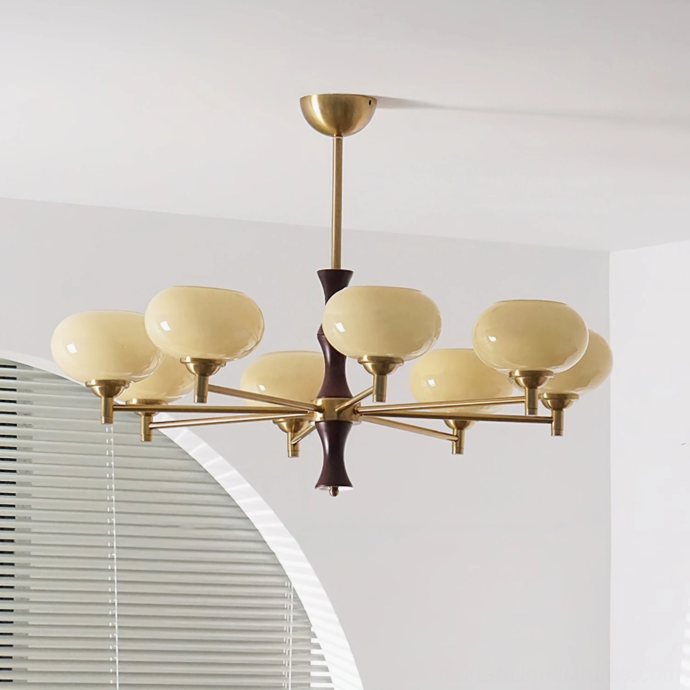 8-head vintage chandelier with beige glass shades and brass frame over dark wood central column in minimalist home with arched louvered window